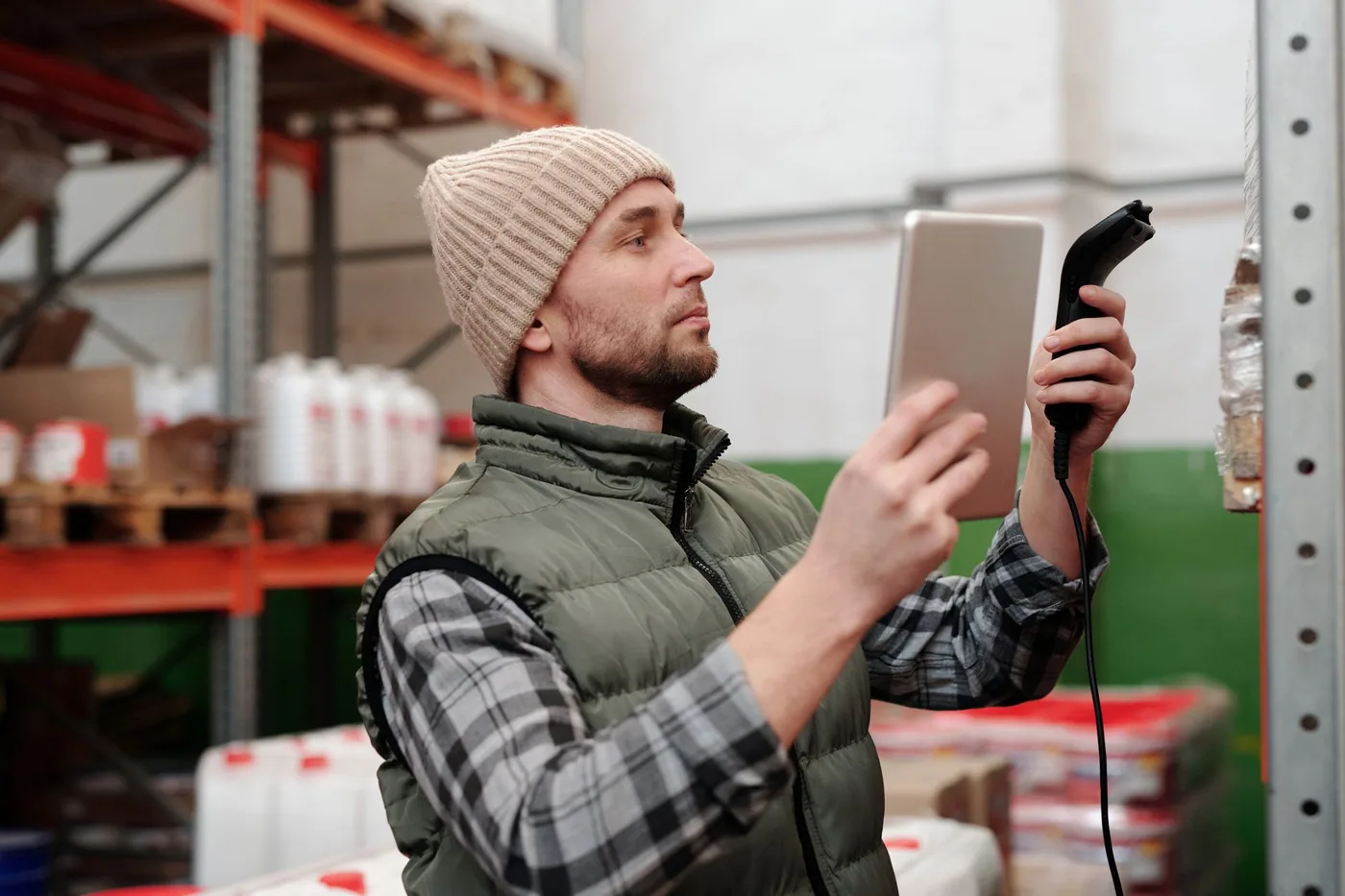 A warehouse worker scanning the barcode label on a carton with a handheld scanner.