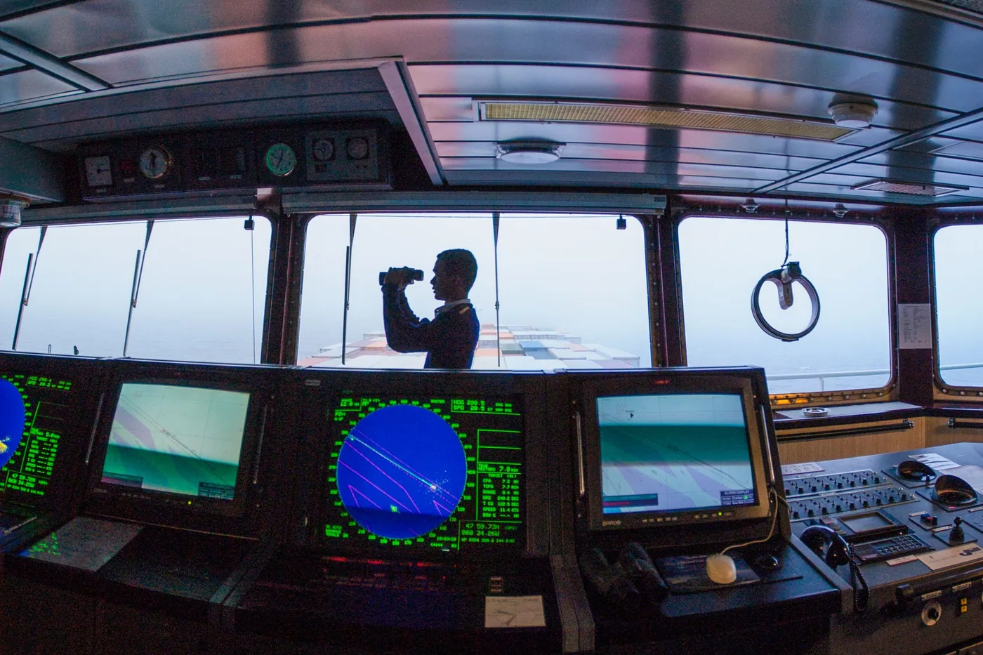 Two operators seated at a multi-monitor workstation in a transport operations room.