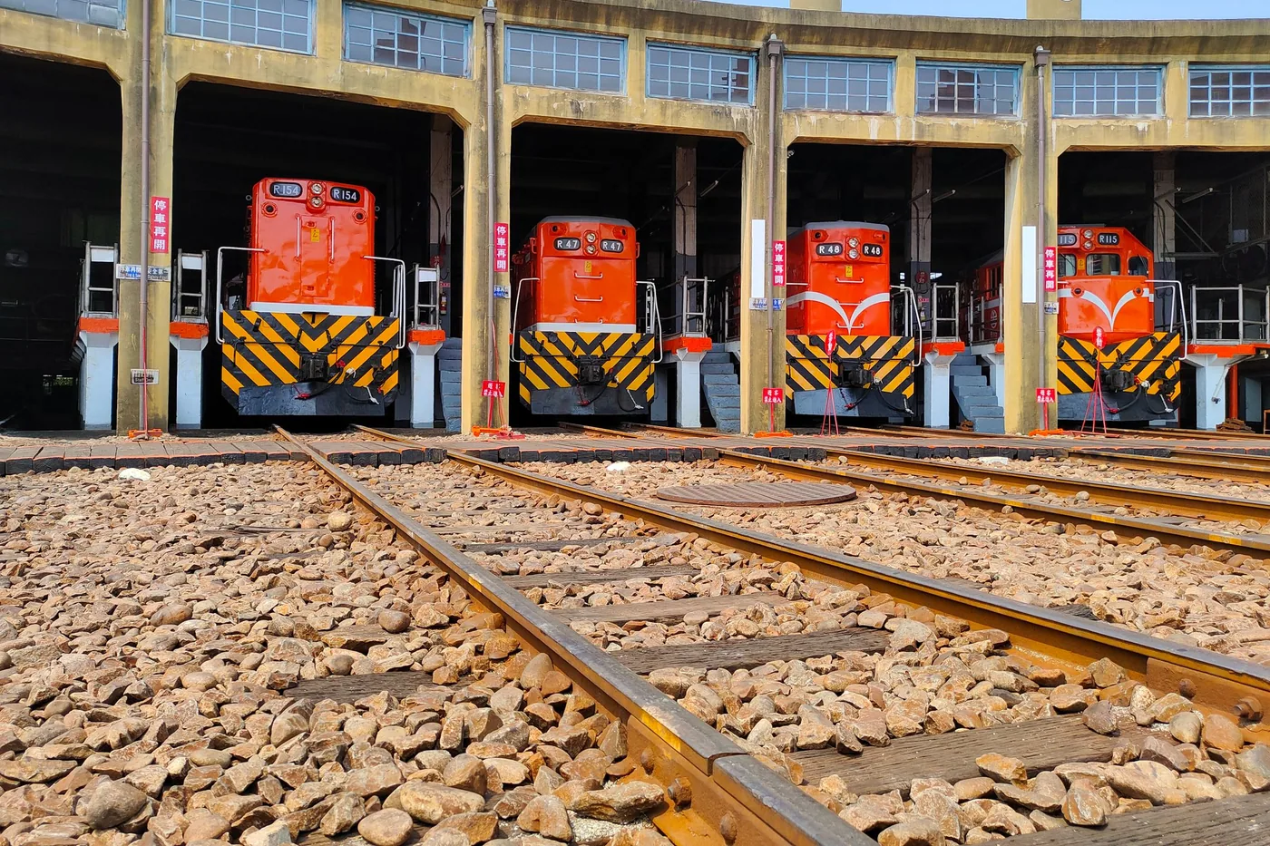 A rail technician working on a train inside a maintenance depot shed.