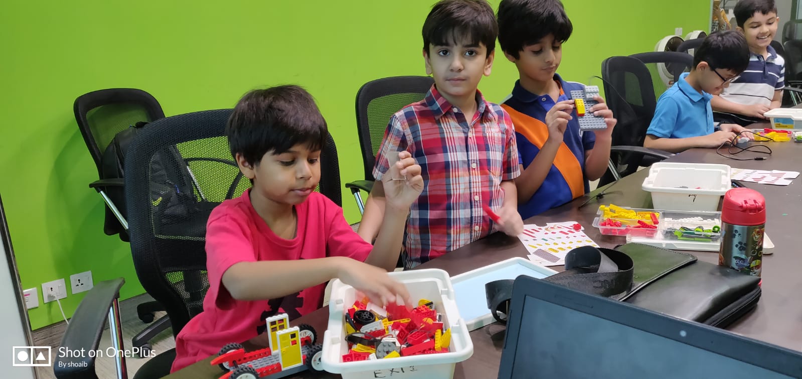 Kids in a class proudly holding the electronic builds they have just assembled